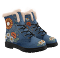 Daisy Winter Boots mockup - three-quarter view of the pair, cream plush trim round each collar, black laces through open eyelets with two solid studs above, a rust and gold sunflower under the trim on one side with a teal cornflower, an orange-red poppy and white daisies below it, and cream-white daisies across each toe on washed denim blue.