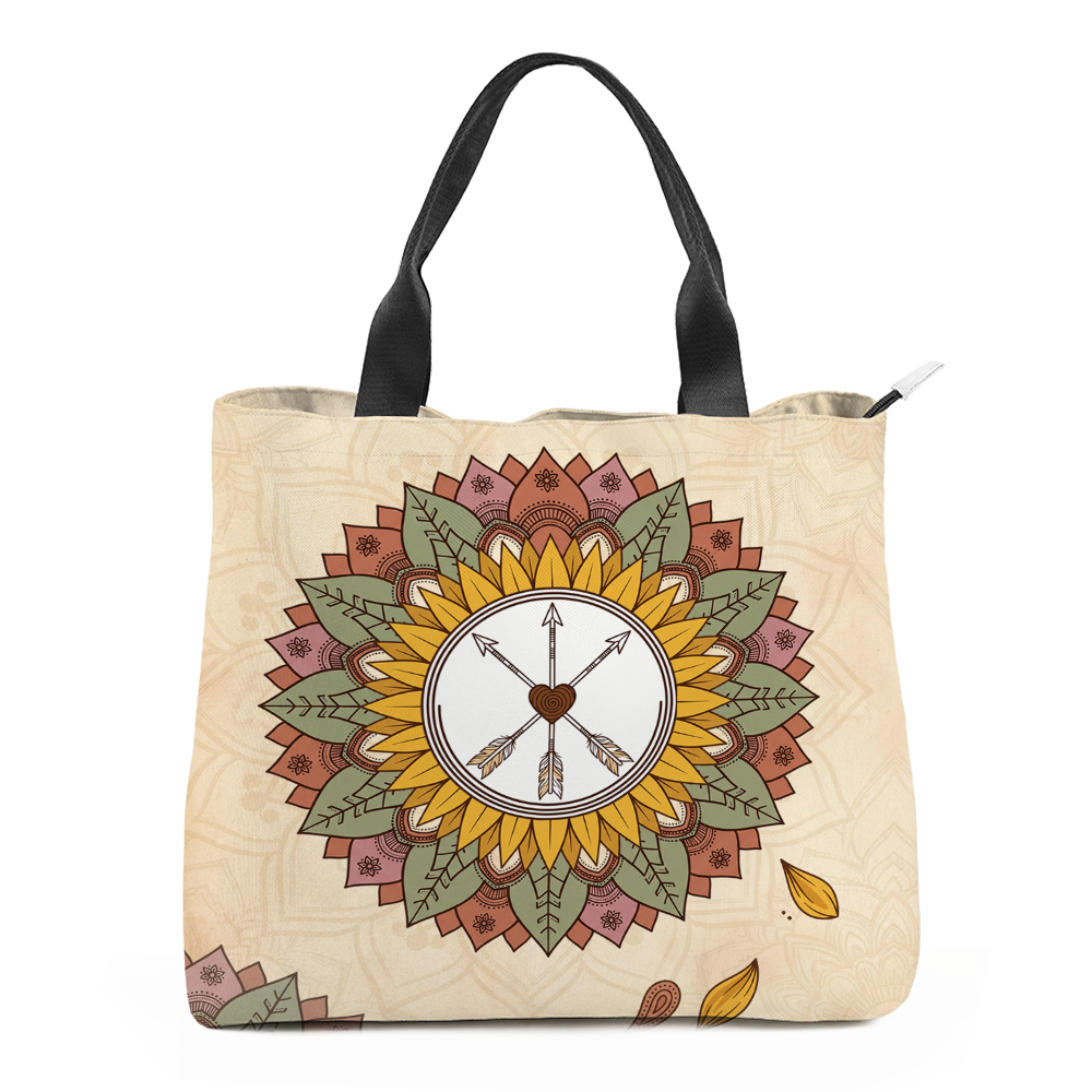 Joni Tote Bag mockup - sunflower mandala centred on cream, a white disc at its heart holding three crossed arrows and a brown spiral heart, golden petals ringed by olive-green leaves and terracotta and dusty-rose outer petals, black webbing handles