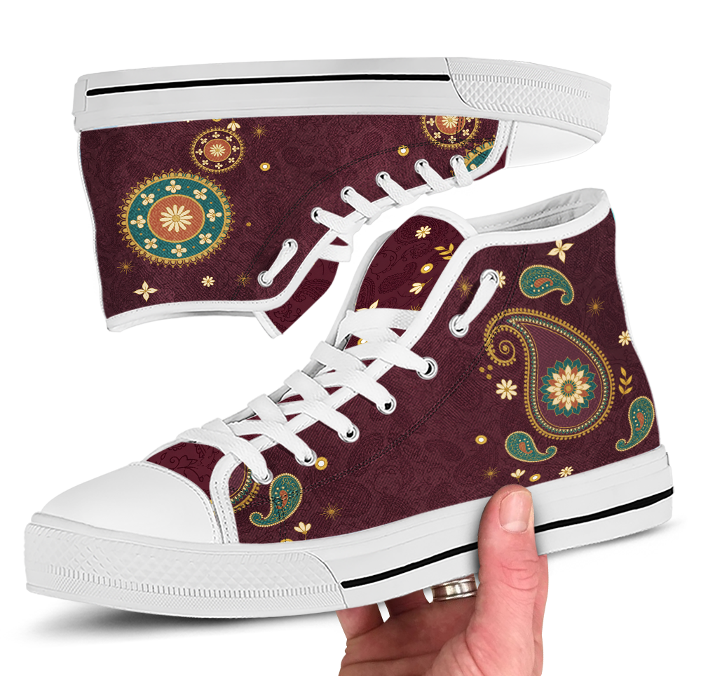 Paisley High Top Sneakers with the White sole - close view of both shoes, one upside down above and one held in a hand below, white sole and white laces through silver eyelets, dark wine upper carrying a boteh teardrop and gold roundels