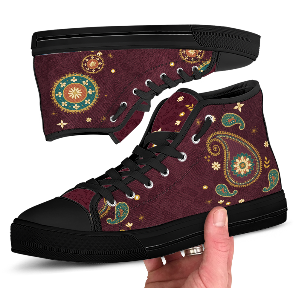 Paisley High Top Sneakers with the Black sole - close view of both shoes, one upside down above and one held in a hand below, black sole and black laces through silver eyelets, dark wine upper carrying a boteh teardrop and gold roundels