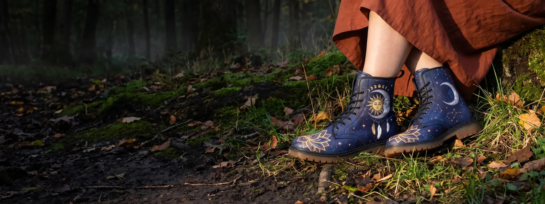 Sun and moon boots worn on a mossy forest path at dusk, under the rust linen hem of a long skirt