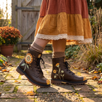 Sunny Leather Boots — on the feet in slouched oatmeal socks below a rust and mustard tiered skirt, on a brick path by a garden gate, sunflower with a peace-sign centre on dark brown